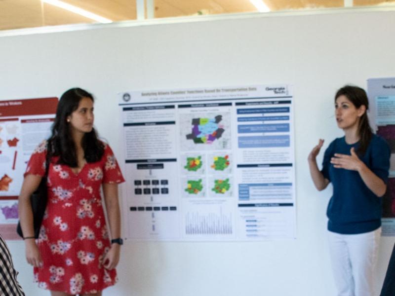 Picture of a faculty explaining to students in a poster session