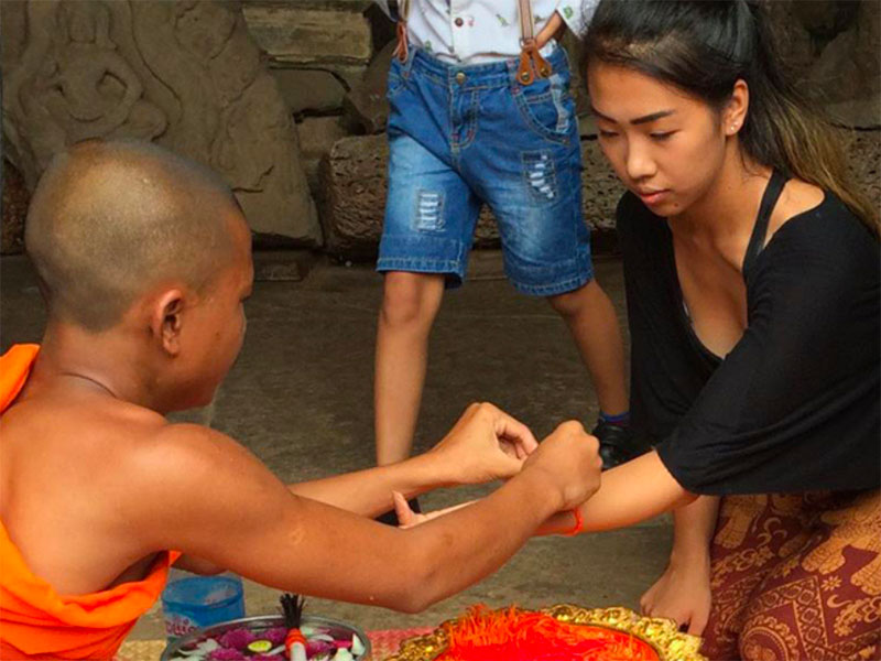 A student gets a bracelet from a monk